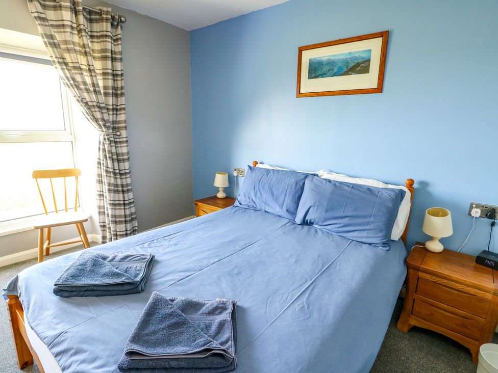 A bedroom with a bed and nightstand at Bodlasan Groes House in Llanfachraeth