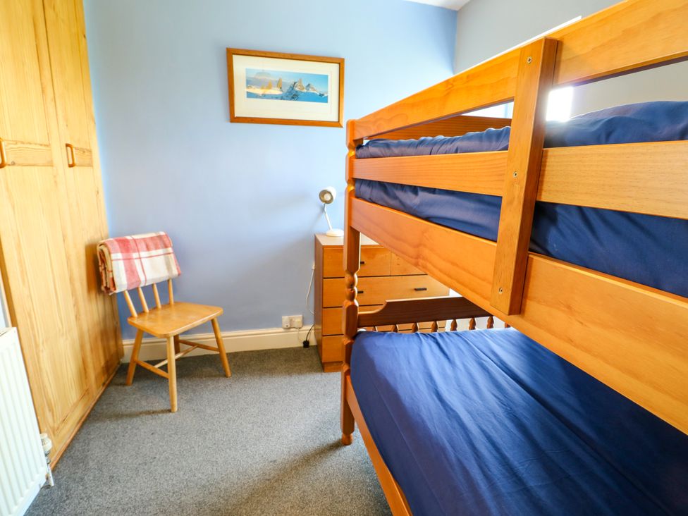 A bedroom with a bunk bed and a chair at Bodlasan Groes House Llanfachraeth