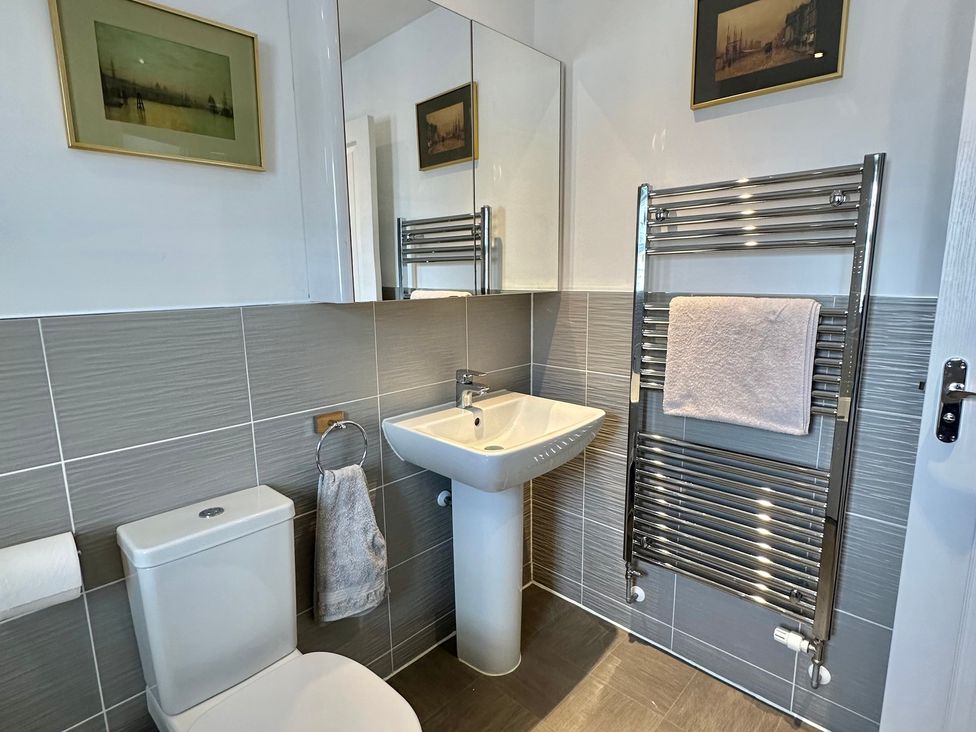 A bathroom featuring a toilet, wash basin, towel rail, and mirror at 2 Clarke Close Cottenham