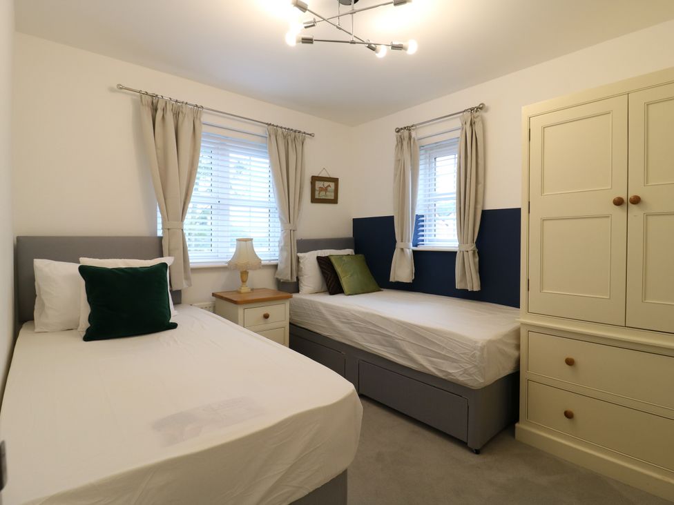 A bedroom with two beds and a lamp at 2 Clarke Close in Cottenham