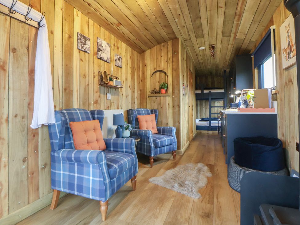 A living room with blue chairs and a kitchen area at The Suffolk in Knutsford