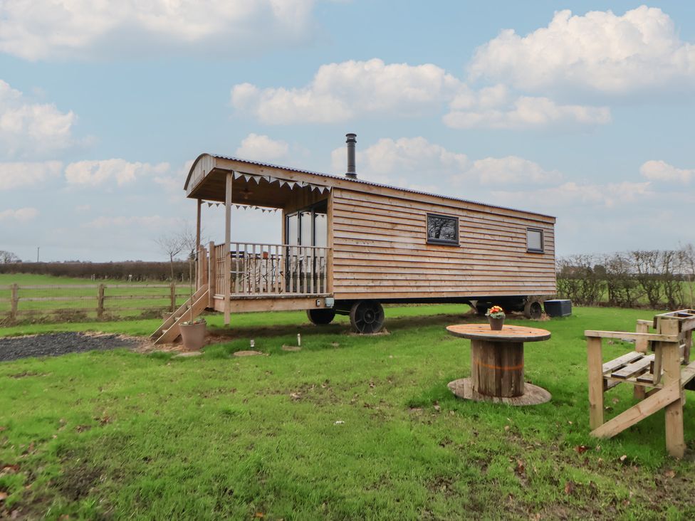 A wooden cabin with a porch and table outside at The Suffolk in Knutsford