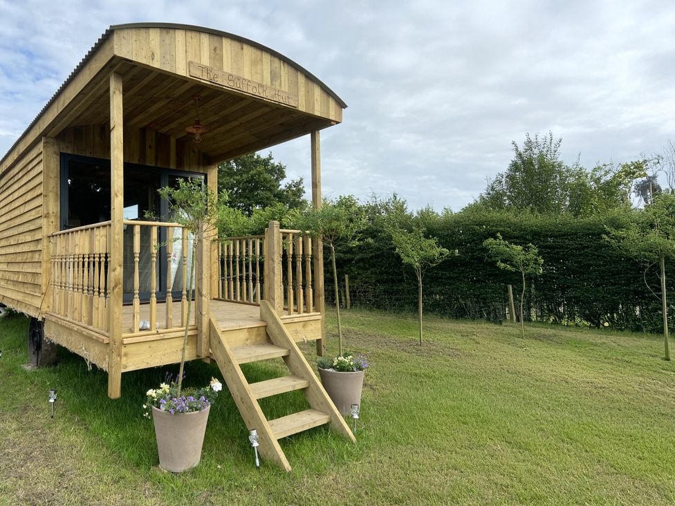 A wooden cabin with steps and planters at The Suffolk Hut in Lower Peover, Cheshire