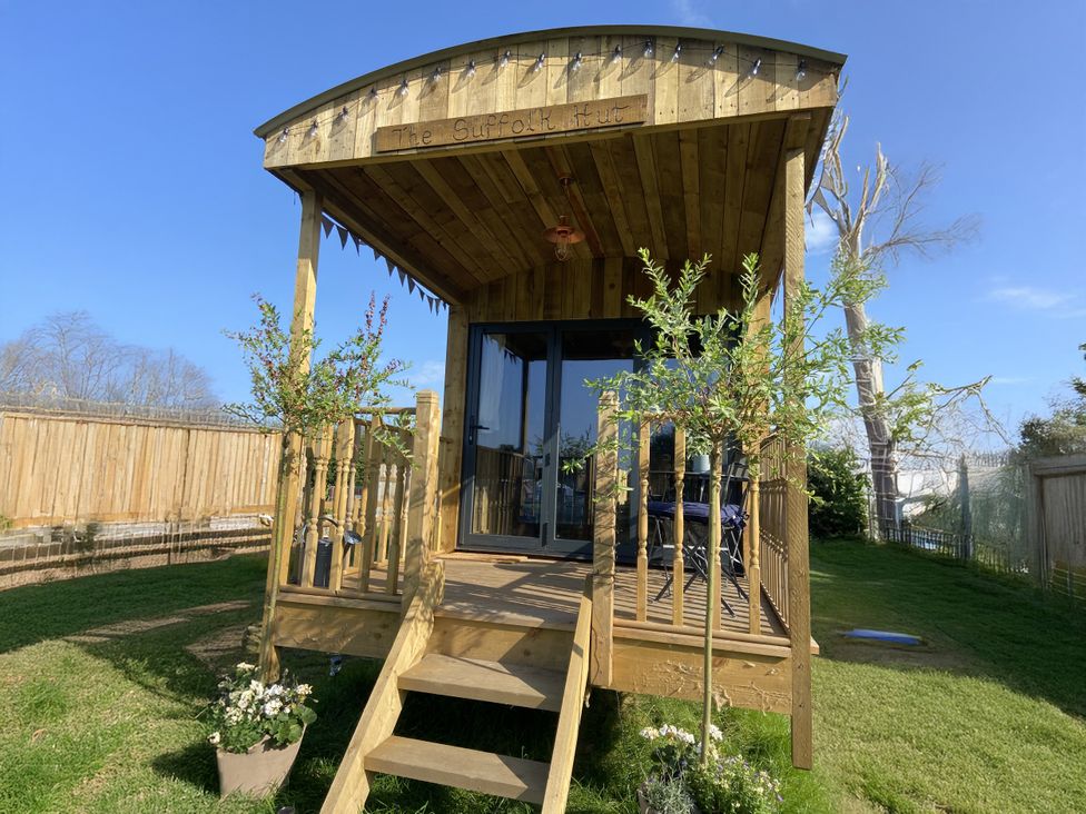 A wooden hut with a deck and plants at The Suffolk Hut in Lower Peover, Cheshire