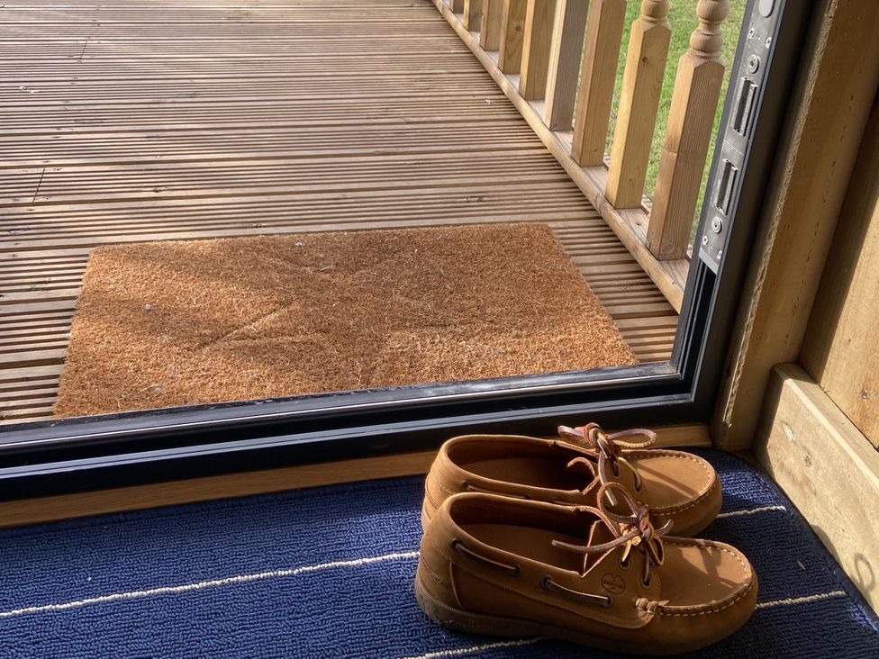 Shoes and a door mat by a sliding door at The Suffolk Hut, Lower Peover, Cheshire