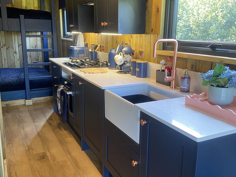 A kitchen with stove, sink, and bunk bed at The Suffolk Hut in Lower Peover, Cheshire
