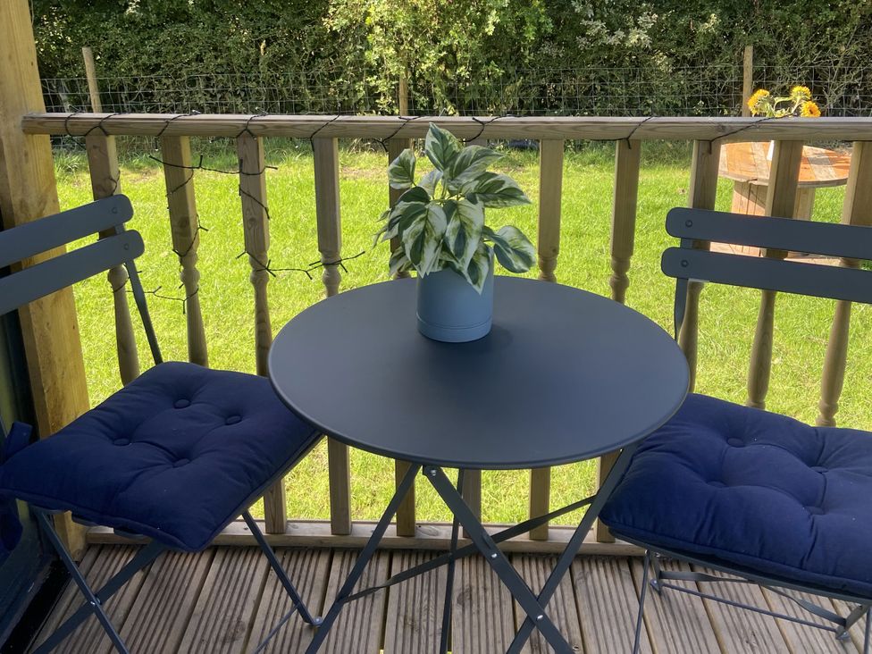 A table with chairs and a plant on a deck at The Suffolk Hut in Lower Peover, Cheshire
