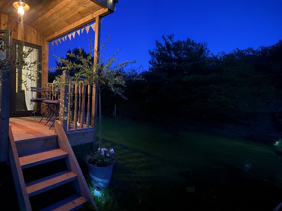 An outdoor porch with stairs, table, chairs, and light at The Suffolk Hut in Lower Peover, Cheshire