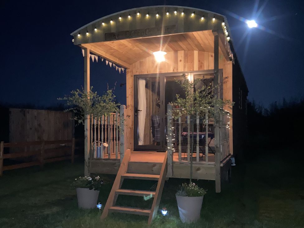 An exterior view of a small wooden hut with decorative lights at The Suffolk Hut in Lower Peover, Cheshire