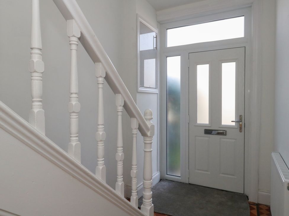 A hallway with a staircase and front door at 93 Abbotsbury Road in Weymouth