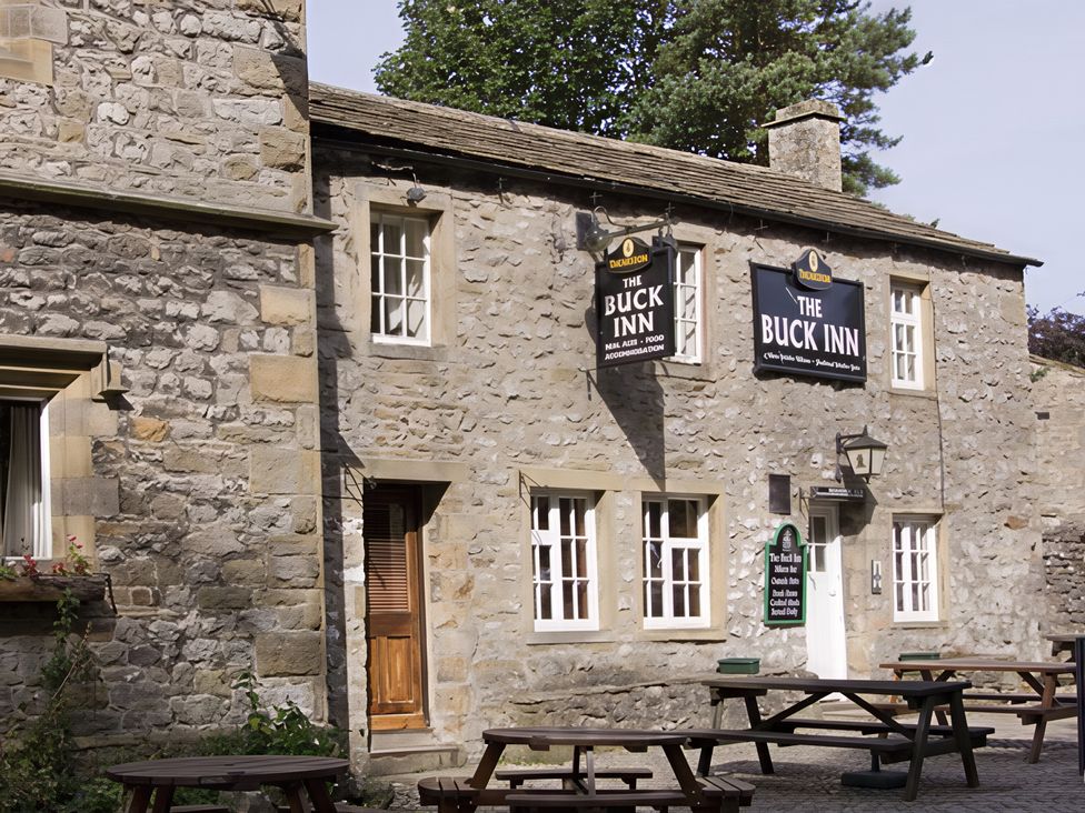 A pub exterior with tables and signs at The Buck Inn in Skipton