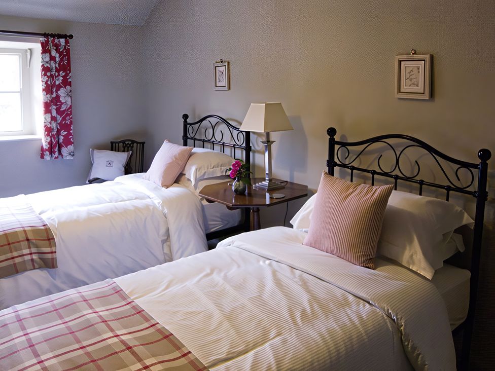 A bedroom with two beds and a table at Town Head Farm in Skipton