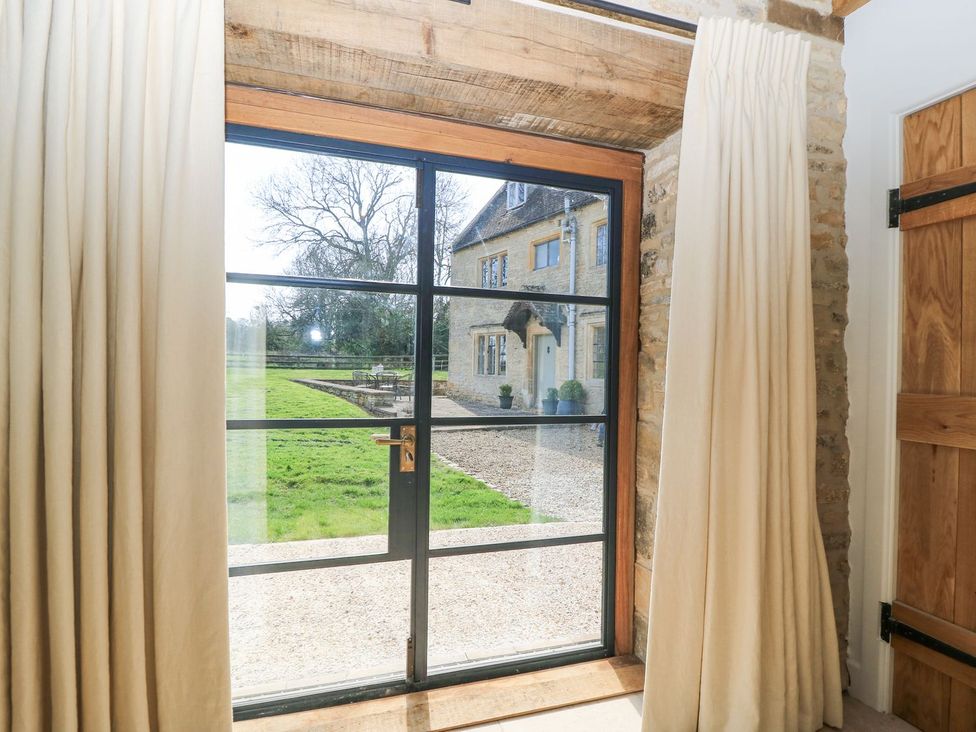 A view through a window with curtains at The Forge in Broadway near Stow-On-The-Wold
