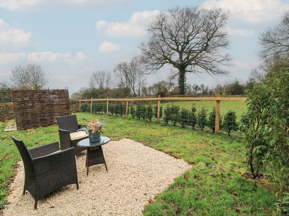 An outdoor seating area with a table and chairs in a garden at The Forge in Broadwell near Stow-On-The-Wold