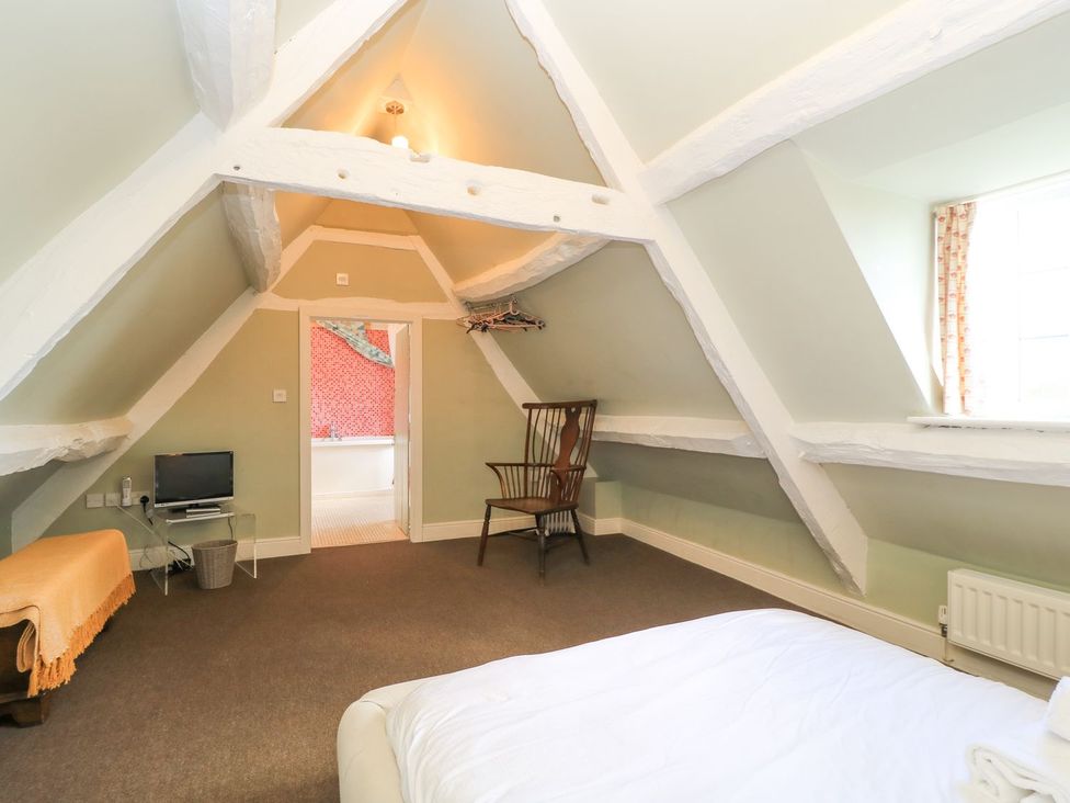 A bedroom with a chair and television at The Smithy in Stow on the wold