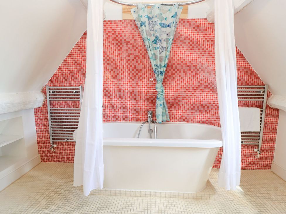 A bathroom with a bathtub and towel rail at The Smithy in Stow on the wold