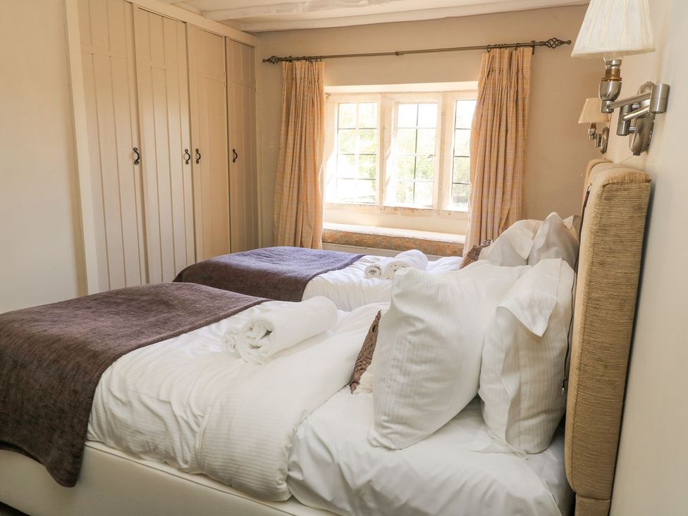 A bedroom with two beds and a window at The Smithy in Stow on the wold