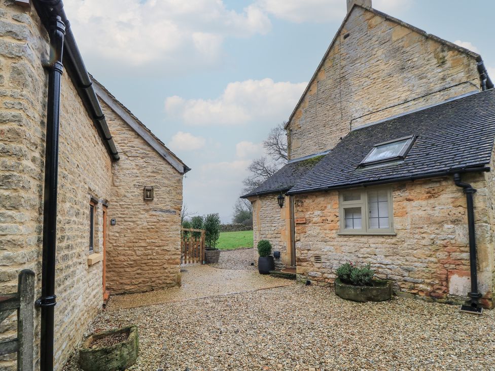 An outdoor view of two stone buildings and a gravel path at The Smithy in Stow-On-The-Wold