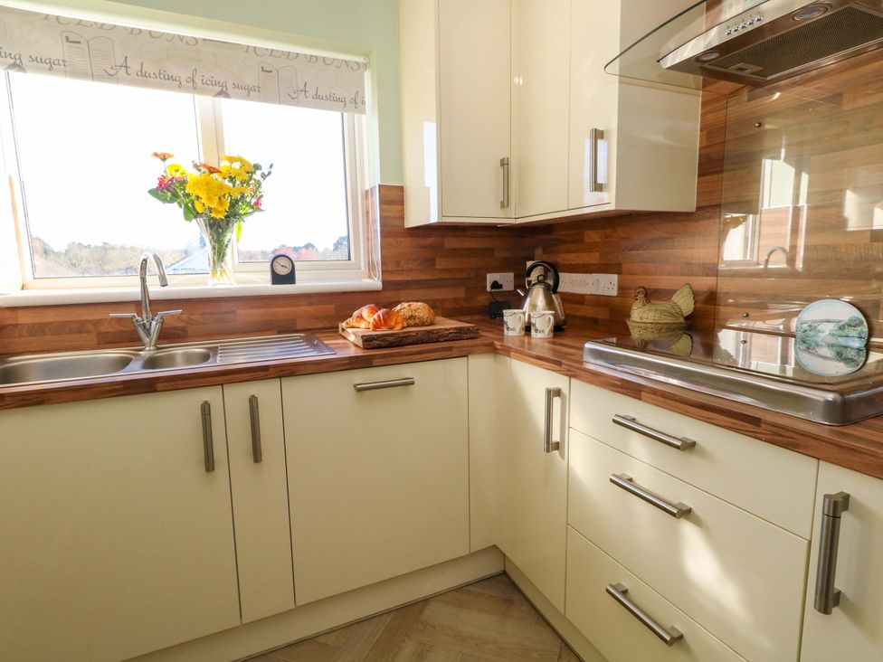 A kitchen with a sink, flowers on the window, and bread on a cutting board at 46 Chafeys Avenue 