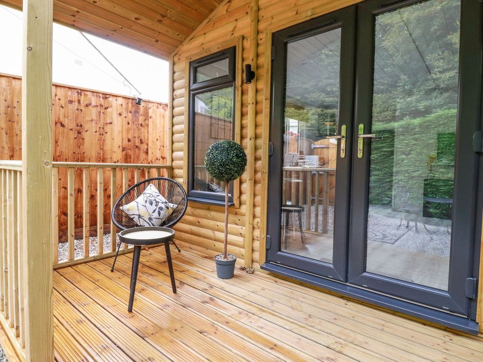 An outdoor deck with a chair and table at St. Chad's Lodge in Bodmin