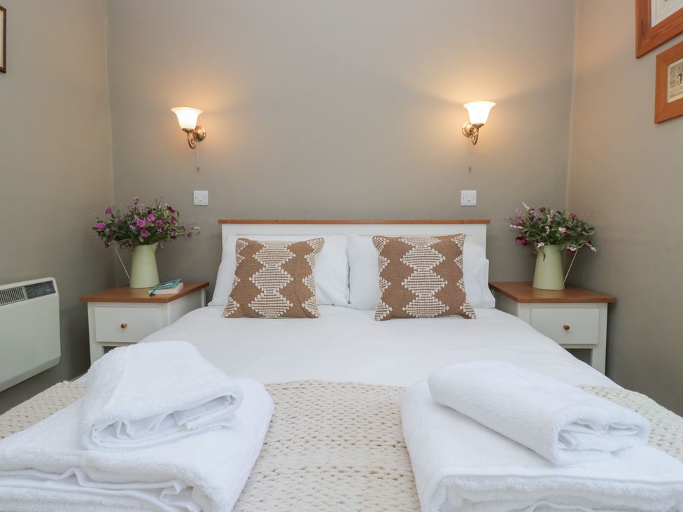 A bedroom with a bed and flowers on the nightstand at Flat 4 Tower House in Grange-Over-Sands