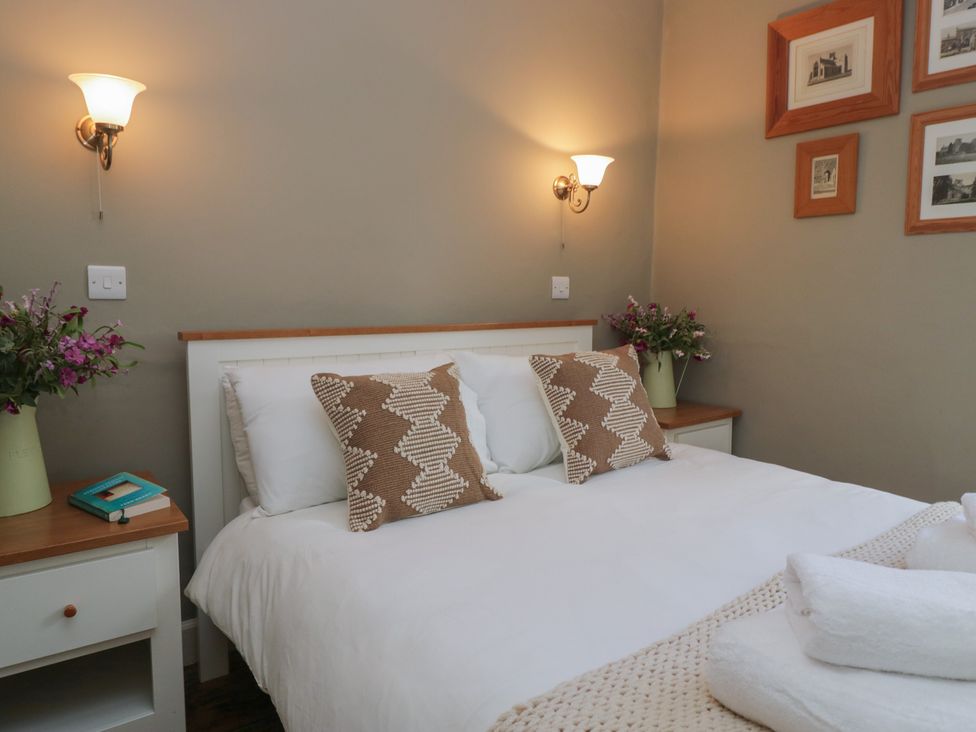 A bedroom with a bed, nightstand, and decorative items at Flat 4 Tower House Grange-Over-Sands