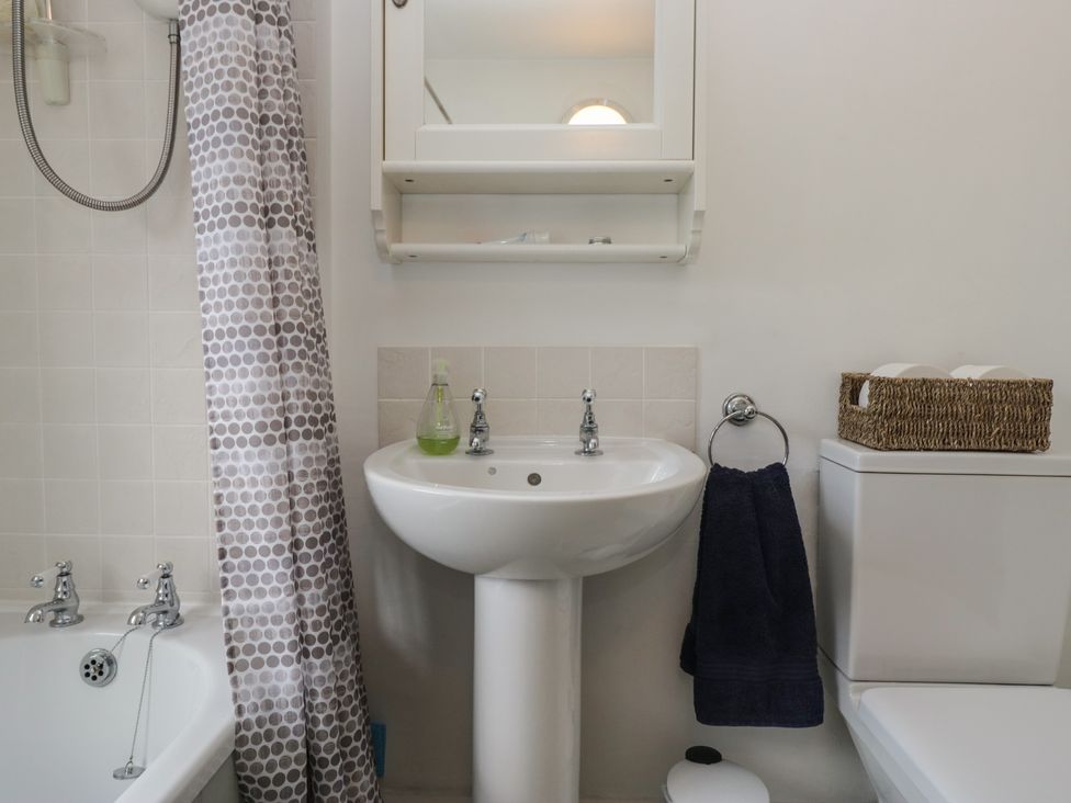A bathroom with a sink, mirror, shower curtain, and toilet at Flat 4 Tower House in Grange-Over-Sands