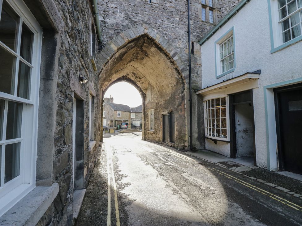 A street view with an arched entrance and stone buildings at Flat 4 Tower House Grange-Over-Sands