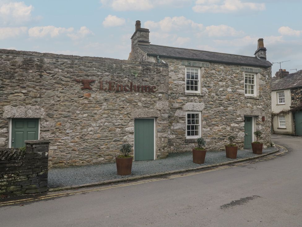 A stone building with green doors and potted plants at Flat 4 Tower House Grange-Over-Sands
