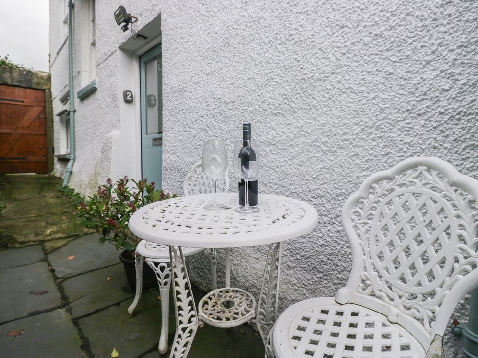 A table with a wine bottle and glass on an outdoor patio at Flat 4 Tower House in Cartmel