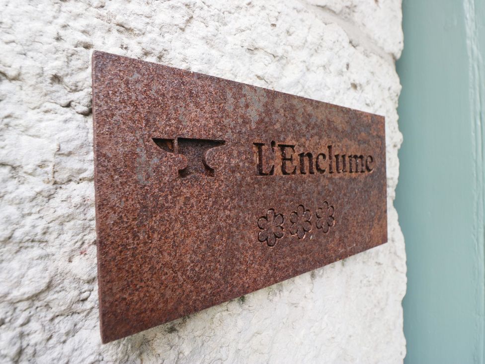 A metal plaque with the name L'Enclume on a wall
