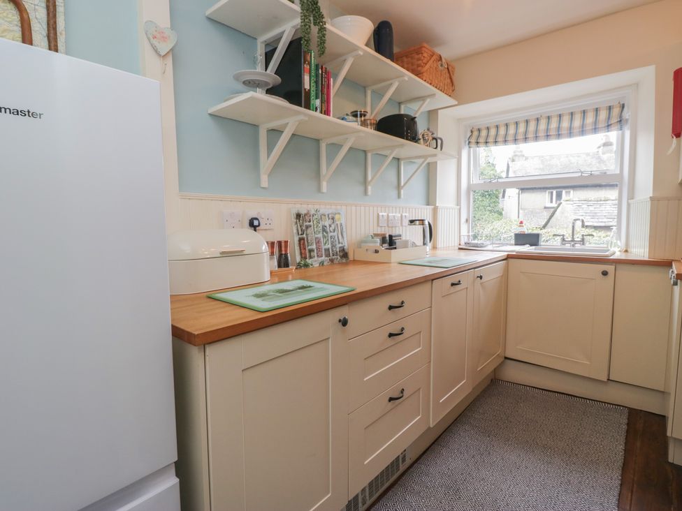 A kitchen featuring a fridge, countertop, sink, and shelf at Flat 4 Tower House in Cartmel