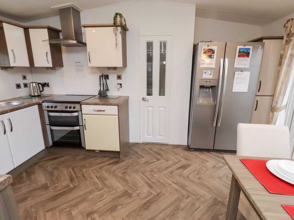 A kitchen with appliances and dining table at Chloe's Cabin in Felmoor Holiday Park near Felton