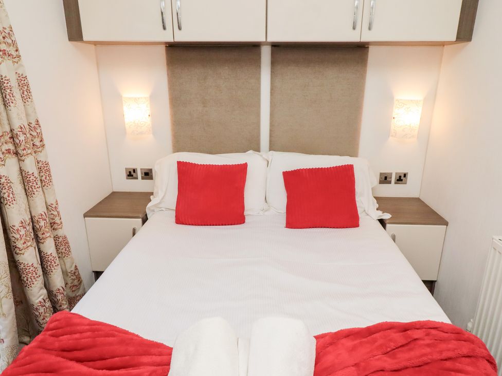 A bedroom with a bed and bedside tables at Chloe's Cabin near Felmoor Holiday Park