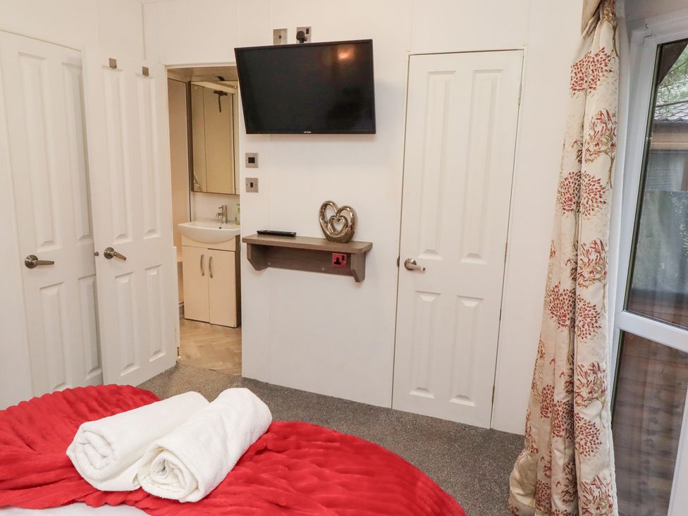 A bedroom with a television and towels on the bed at Chloe's Cabin near Felmoor Holiday Park near Felton