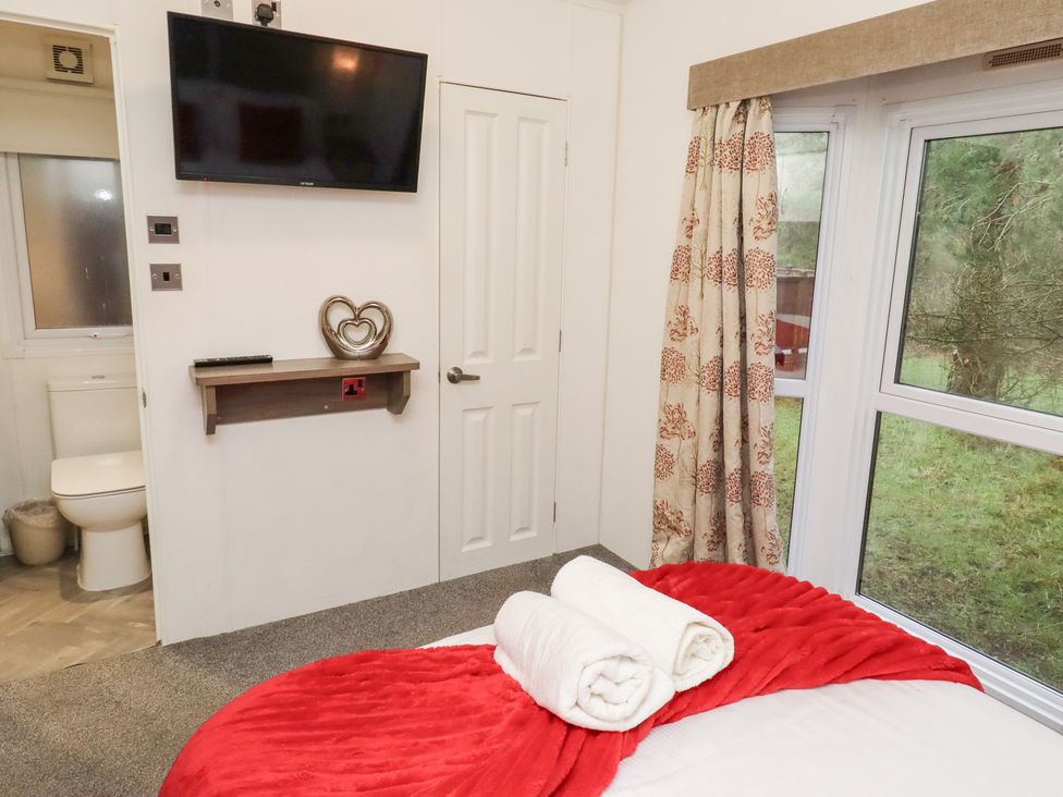 A bedroom with a bed and television at Chloe's Cabin near Felmoor Holiday Park