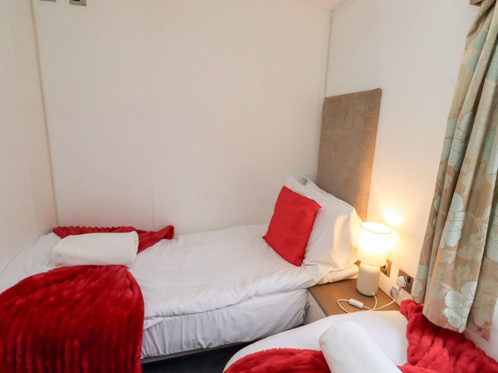A bedroom with two beds and a lamp at Chloe's Cabin near Felmoor Holiday Park