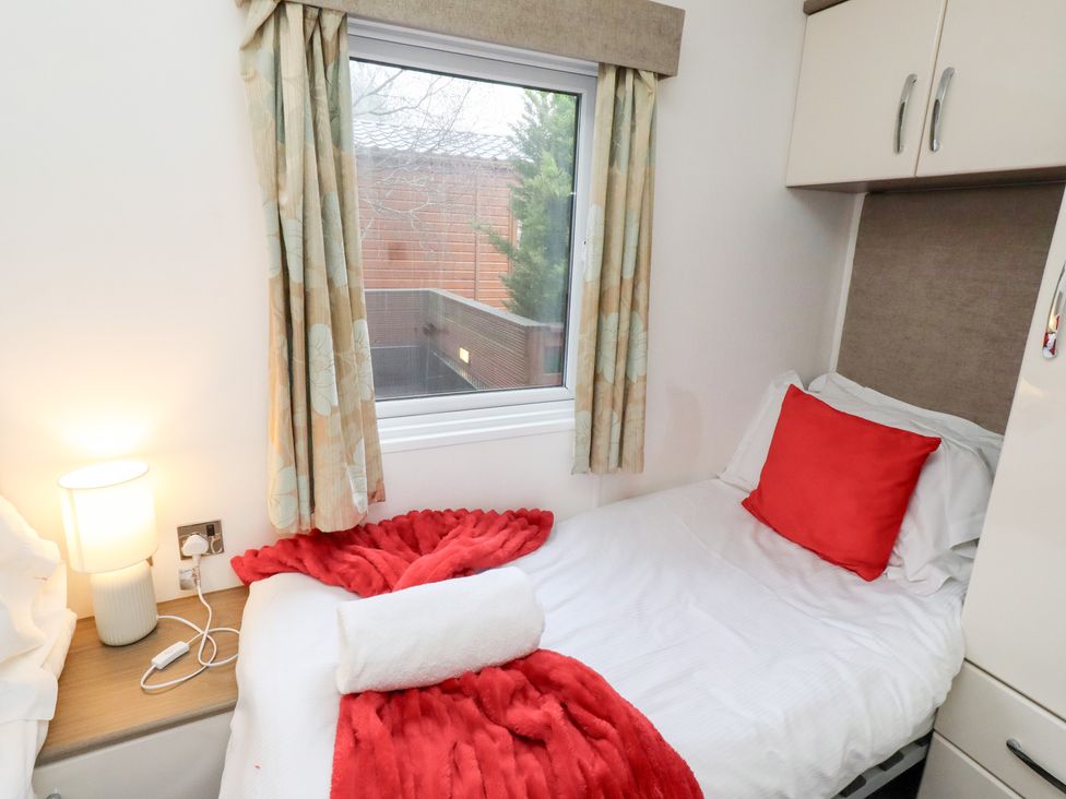 A bedroom with a bed and window at Chloe's Cabin Felmoor Holiday Park near Felton