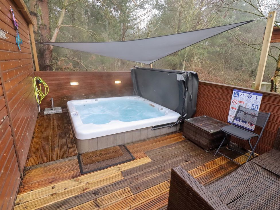 An outdoor area with a hot tub and seating at Chloe's Cabin near Felmoor Holiday Park near Felton