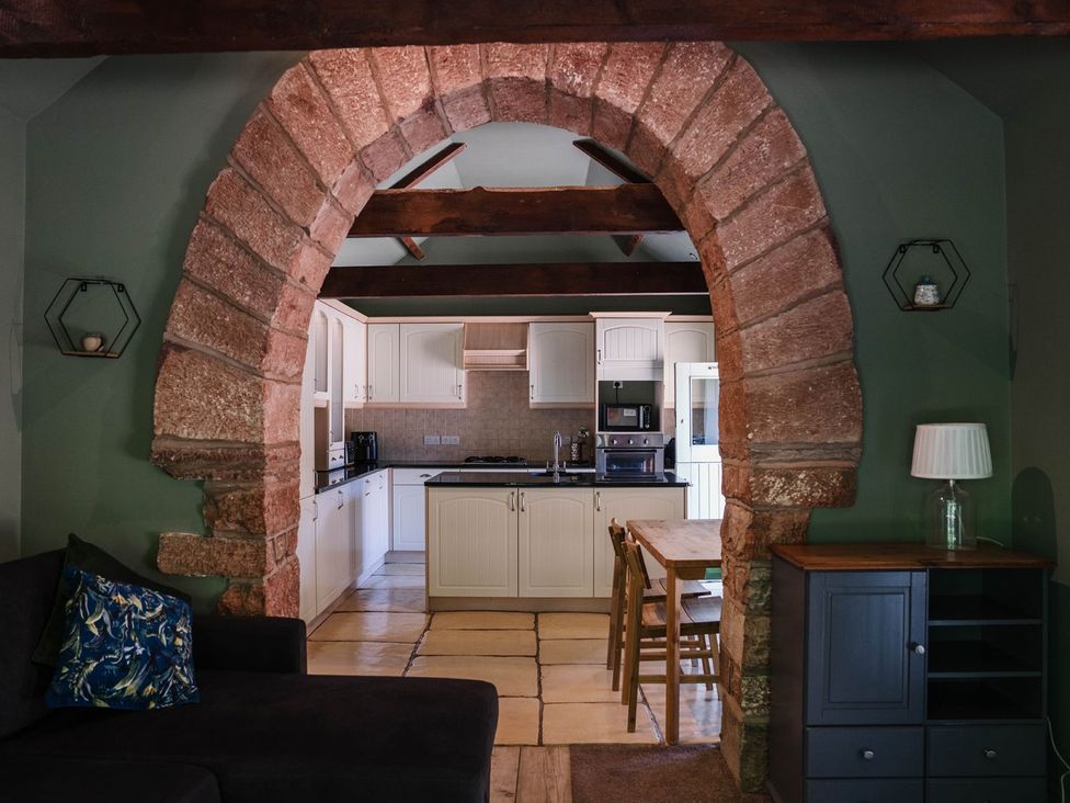 A kitchen with an archway and dining table at Carwinley Mill House Cottage Carwinley near Longtown