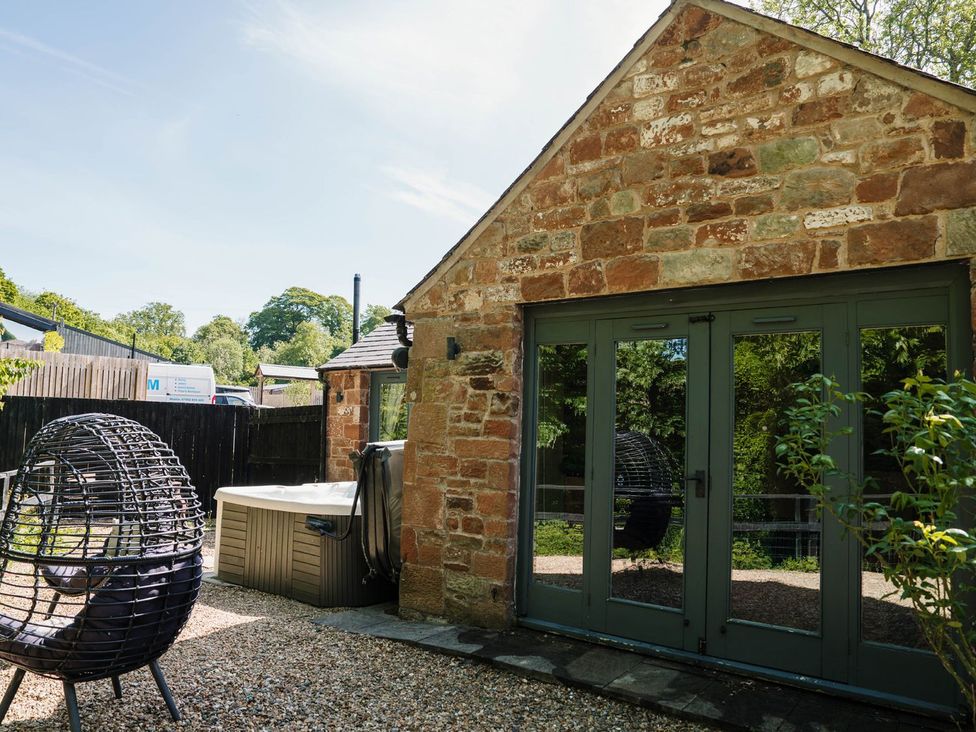 A house with a hot tub and chair in the garden at Carwinley Mill House Cottage Carwinley near Longtown