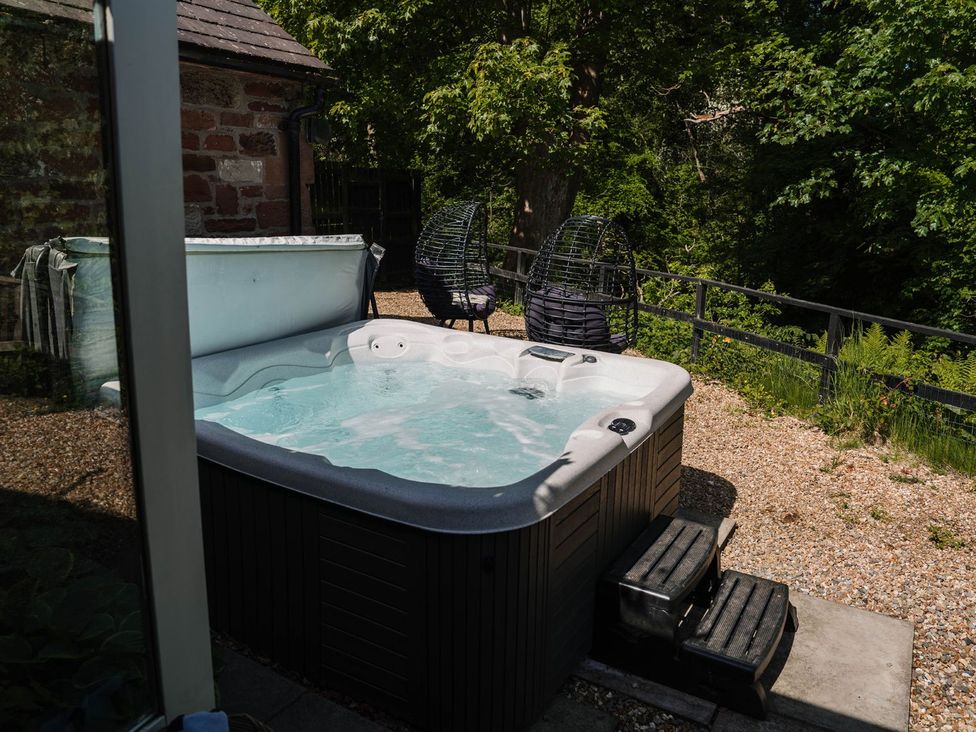 An outdoor area with a hot tub and hammock chairs at Carwinley Mill House Cottage Carwinley near Longtown