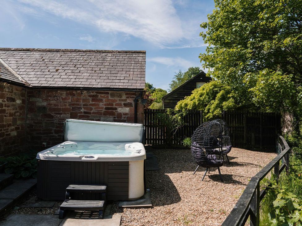 A garden with a hot tub and an outdoor chair at Carwinley Mill House Cottage in Carwinley near Longtown