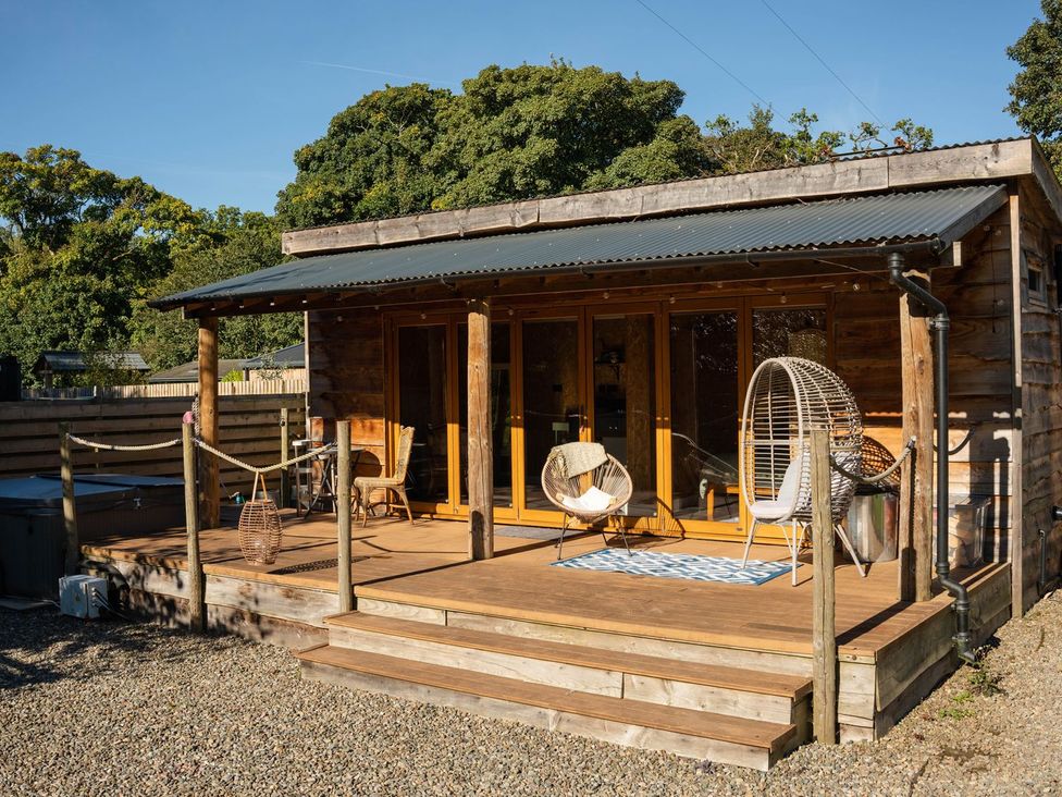 An outdoor area with wooden cabin and seating at The Chard in Carlisle