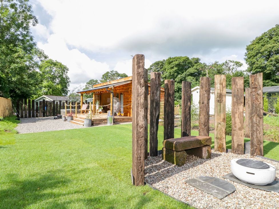 A garden with a wooden deck and fire pit at The Chard in Carlisle