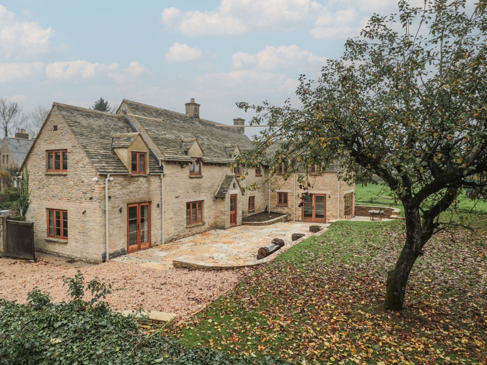 A stone house with a garden and patio at Manor Cottage in Carterton, Oxfordshire
