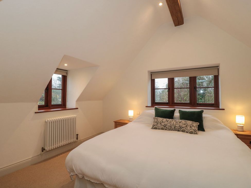 A bedroom with a bed and windows at Manor Cottage in Carterton, Oxfordshire