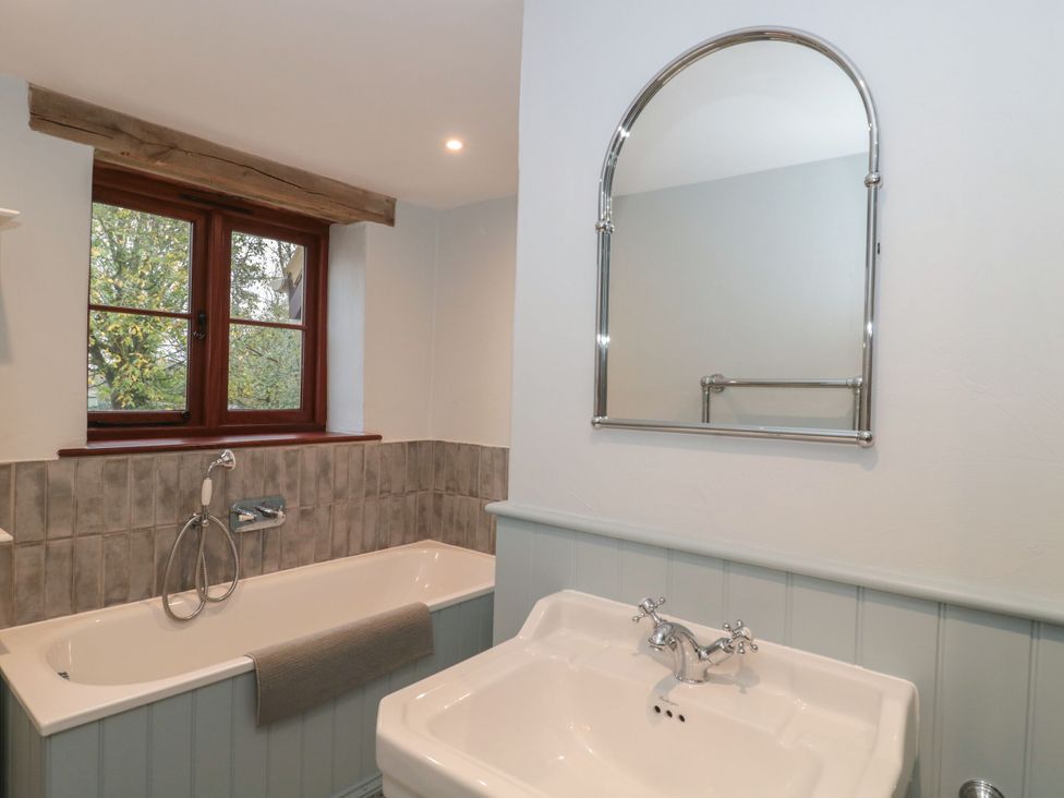 A bathroom with a bathtub and sink at Manor Cottage, Carterton, Oxfordshire