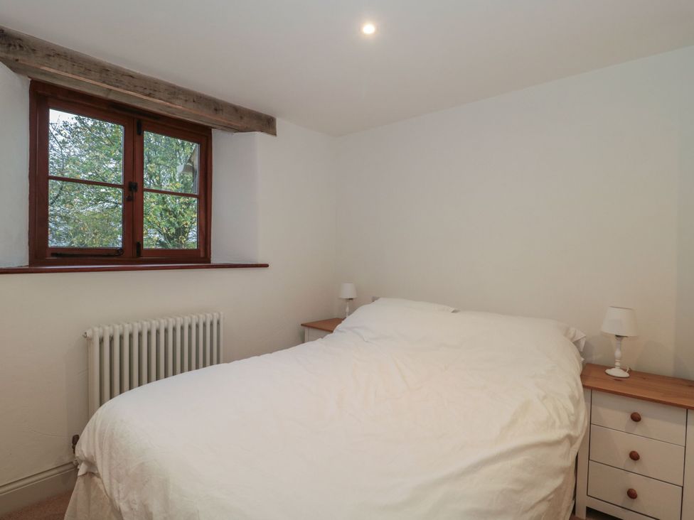 A bedroom with a bed and nightstands at Manor Cottage in Carterton, Oxfordshire