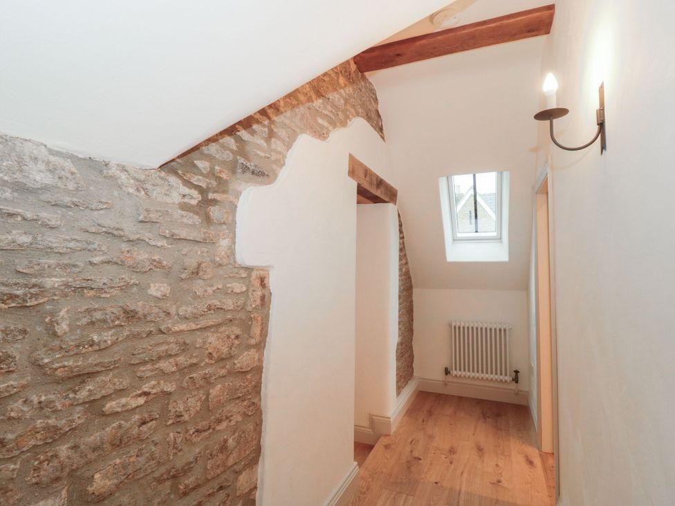 A hallway with stone wall and window at Manor Cottage in Carterton, Oxfordshire